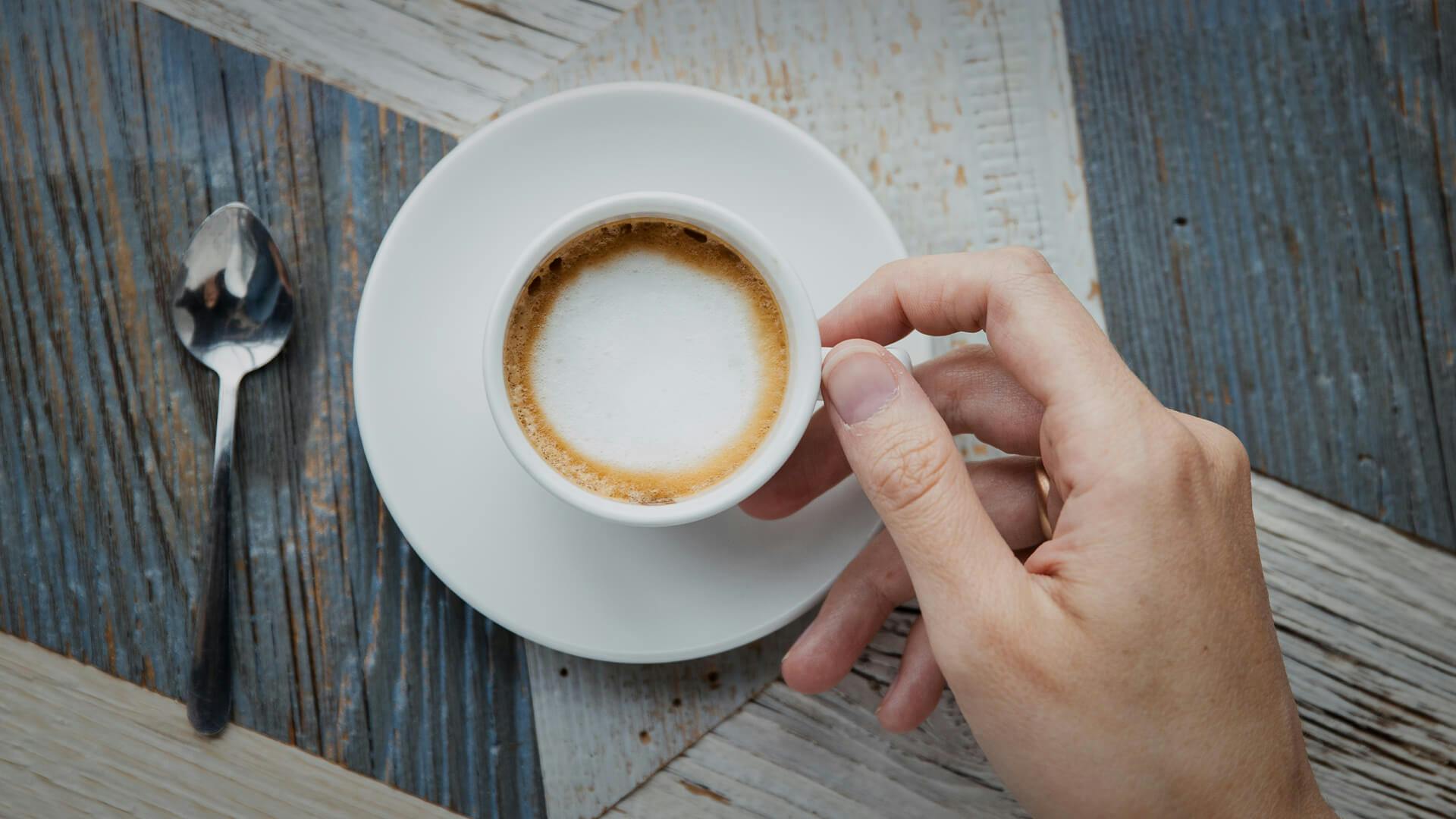 Een kop cappuccino in twee handen
